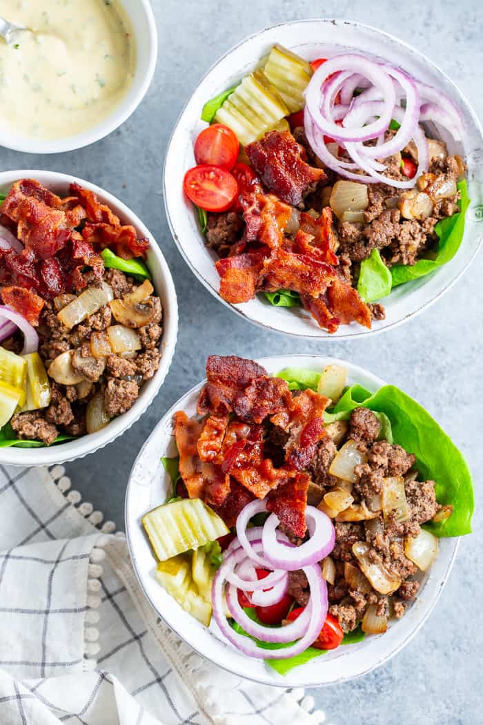 These deconstructed loaded bacon burger bowls have all the goodies you love in a burger!  Sautéed mushrooms and onions, crispy bacon, pickles, tomatoes, red onion and a “cheesy” ranch sauce!  Paleo, Whole30, and keto friendly and seriously delicious!