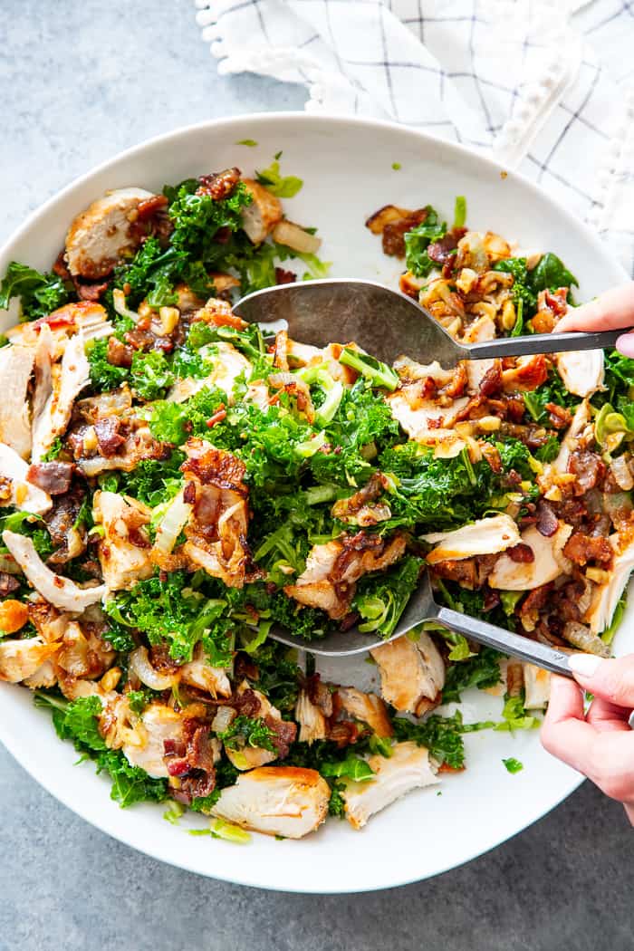This kale salad is packed to the max with goodies!  Kale is tossed with shredded Brussels sprouts, lots of sweet caramelized onions, crispy bacon and grilled chicken plus a super tasty hot bacon dressing.  It’s dairy free and paleo with both Whole30 and keto options. 