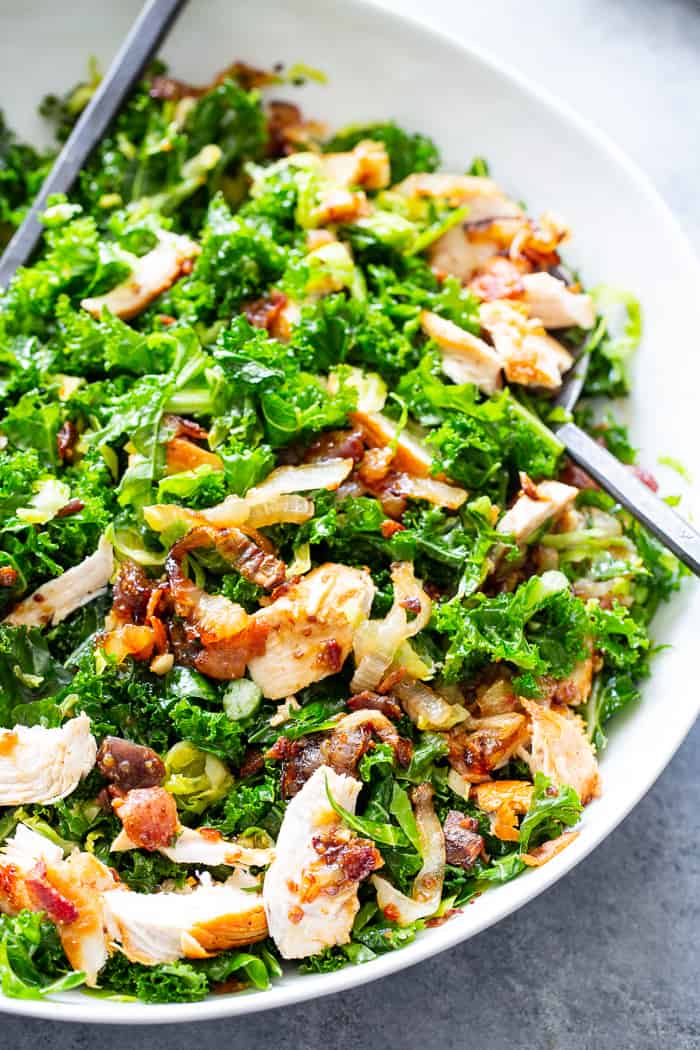 This kale salad is packed to the max with goodies!  Kale is tossed with shredded Brussels sprouts, lots of sweet caramelized onions, crispy bacon and grilled chicken plus a super tasty hot bacon dressing.  It’s dairy free and paleo with both Whole30 and keto options. 