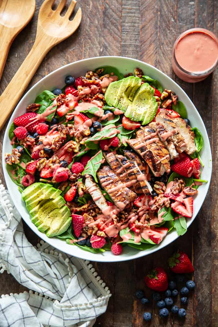 This triple berry grilled chicken salad is packed with flavor with sweet juicy berries, avocado, and a raspberry vinaigrette along with savory grilled chicken, spinach, and walnuts.  It's Paleo, dairy-free, and has a Whole30 friendly option.  Perfect for a light healthy lunch or dinner!