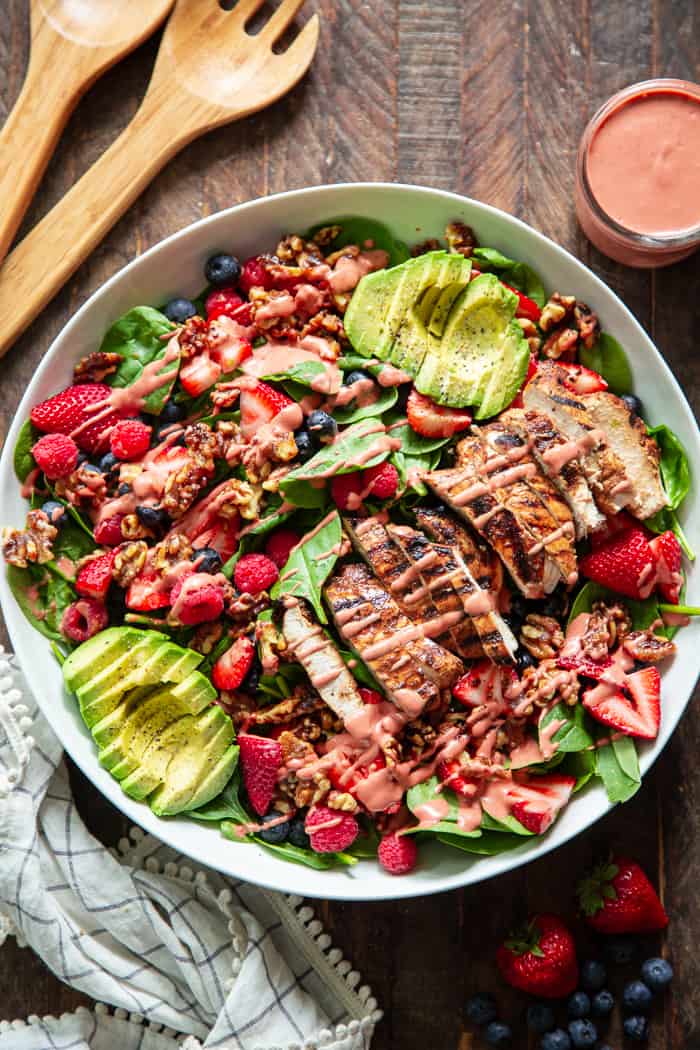 This triple berry grilled chicken salad is packed with flavor with sweet juicy berries, avocado, and a raspberry vinaigrette along with savory grilled chicken, spinach, and walnuts.  It's Paleo, dairy-free, and has a Whole30 friendly option.  Perfect for a light healthy lunch or dinner!