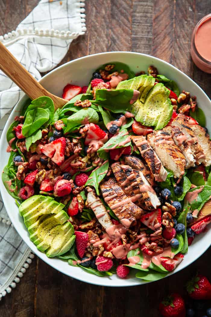 This triple berry grilled chicken salad is packed with flavor with sweet juicy berries, avocado, and a raspberry vinaigrette along with savory grilled chicken, spinach, and walnuts.  It's Paleo, dairy-free, and has a Whole30 friendly option.  Perfect for a light healthy lunch or dinner!