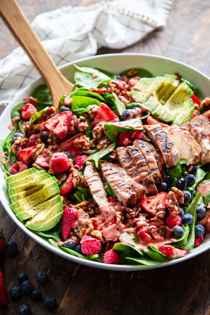 This triple berry grilled chicken salad is packed with flavor with sweet juicy berries, avocado, and a raspberry vinaigrette along with savory grilled chicken, spinach, and walnuts.  It's Paleo, dairy-free, and has a Whole30 friendly option.  Perfect for a light healthy lunch or dinner!