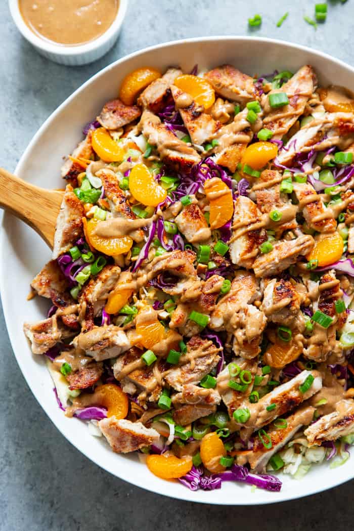 chicken salad in a bowl with purple cabbage, mandarin oranges, and scallions