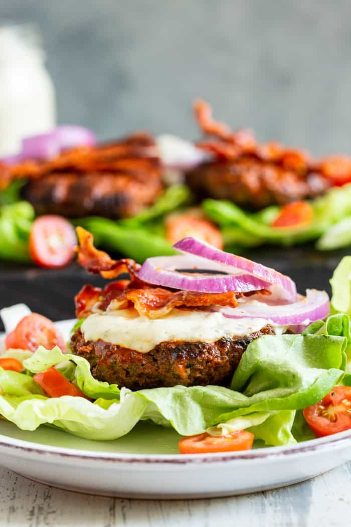 These spicy buffalo burgers are easy to make, and packed with tons of flavor.  Juicy spicy beef burgers are topped with smoky bacon and topped with a homemade cool ranch dressing.  Keep it Whole30 and keto friendly by wrapping in lettuce or serving over a big salad.