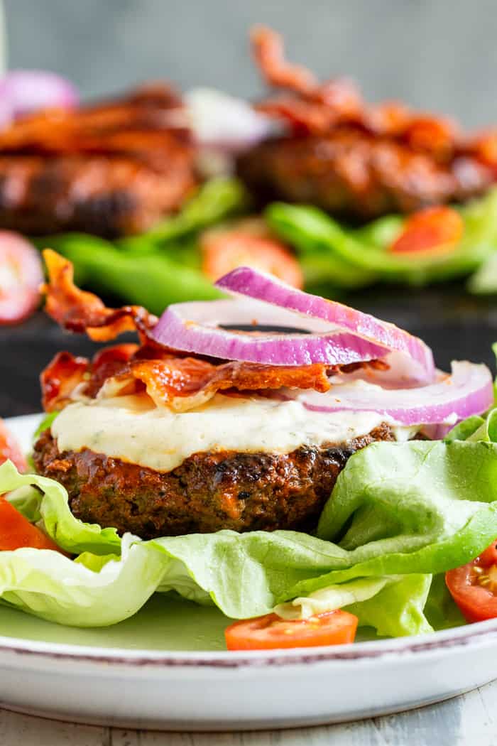 These spicy buffalo burgers are easy to make, and packed with tons of flavor.  Juicy spicy beef burgers are topped with smoky bacon and topped with a homemade cool ranch dressing.  Keep it Whole30 and keto friendly by wrapping in lettuce or serving over a big salad.