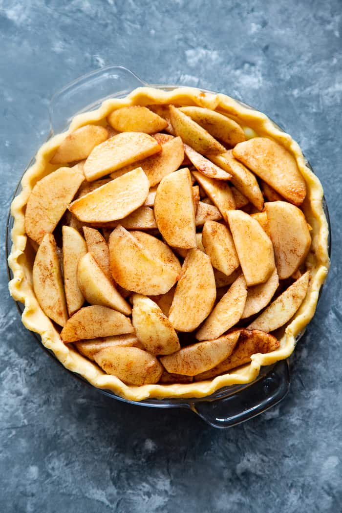 cinnamon coated apple slices layered in an unbaked pie shell