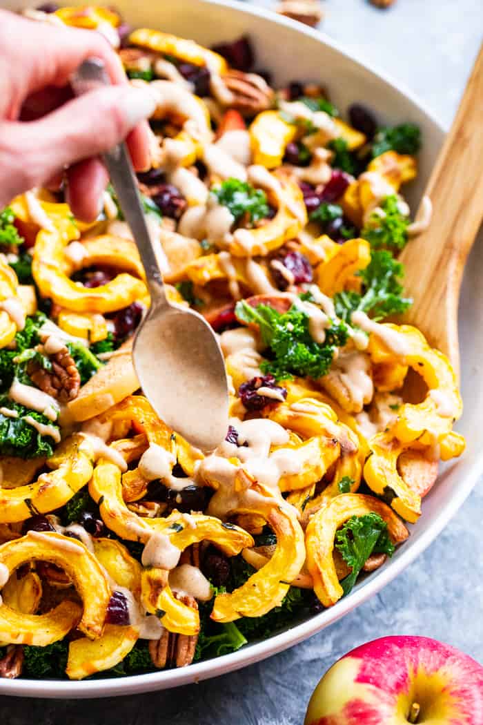 This harvest kale salad is packed to the max with goodies!  Perfectly roasted delicata squash, apples, pecans, and cranberries all tossed in a cider vinaigrette that’s naturally sweetened with dates.  Whole30, Paleo, vegan, and no refined sugar.