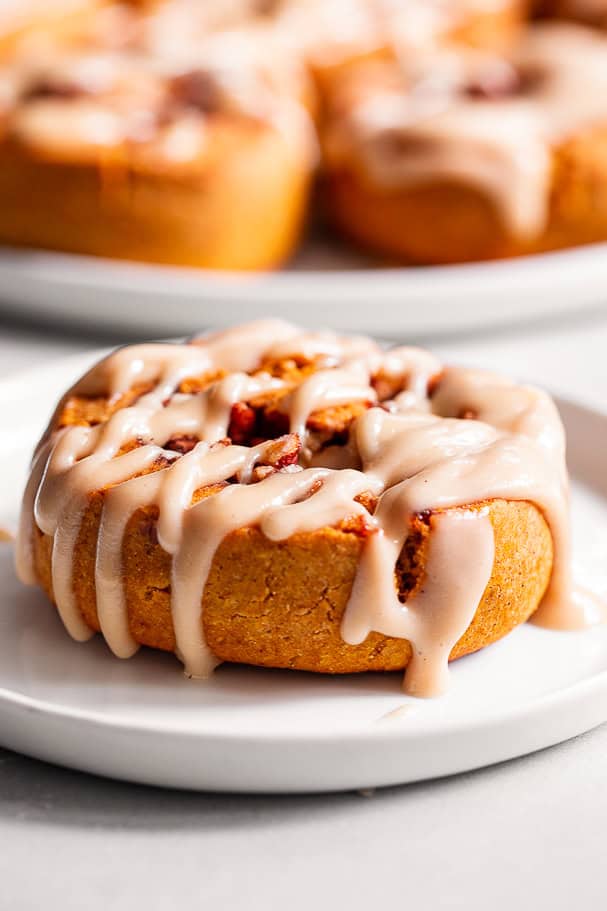 paleo pumpkin cinnamon roll with icing on a white plate