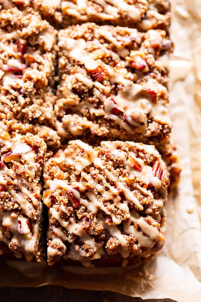 pumpkin cake cut into squares with crumble topping and frosting glaze