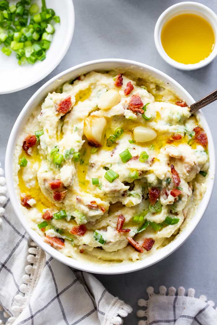 This creamy mashed cauliflower is packed with goodies like roasted garlic, crispy bacon and scallions. It tastes just like loaded mashed potatoes, but without the carbs!  Whole30 compliant, paleo, keto, and dairy-free.