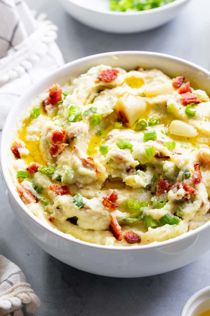 This creamy mashed cauliflower is packed with goodies like roasted garlic, crispy bacon and scallions. It tastes just like loaded mashed potatoes, but without the carbs!  Whole30 compliant, paleo, keto, and dairy-free.