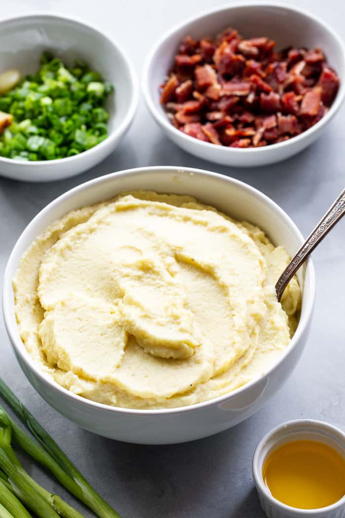 This creamy mashed cauliflower is packed with goodies like roasted garlic, crispy bacon and scallions. It tastes just like loaded mashed potatoes, but without the carbs!  Whole30 compliant, paleo, keto, and dairy-free.