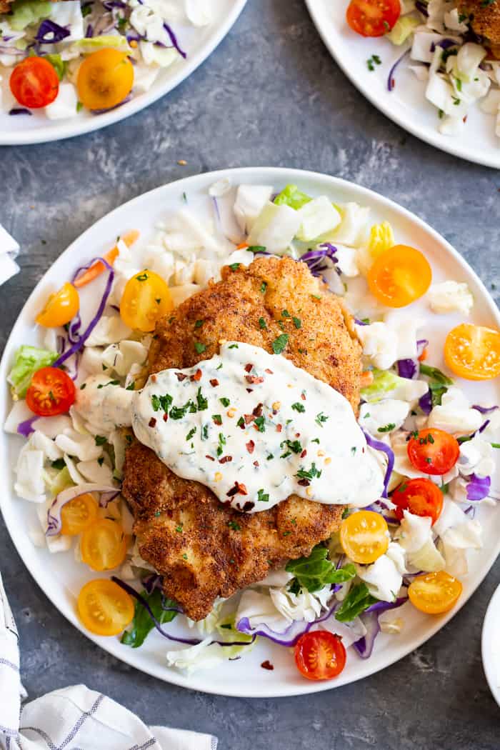 This savory crisp Paleo Chicken Milanese topped with zesty homemade ranch sauce is a quick and easy dinner you’ll want on repeat!  Serve over a salad, spaghetti squash, roasted veggies, or anything you like.  It’s Whole30, Keto friendly, gluten free and dairy free.