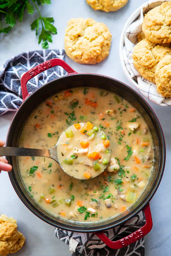 This creamy, cozy and delicious chicken pot pie soup has it all!  A paleo and dairy-free chicken pot pie filling with loads of veggies and savory herbs and the yummiest paleo + low carb biscuits!  The whole family will love this  healthy, hearty soup on cold winter nights.