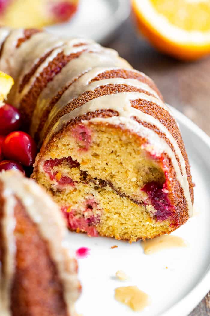 This Paleo Cranberry Orange Bundt Cake is perfectly moist  bursting with sweet orange flavor and tart juice cranberries.  A cinnamon swirl plus sweet maple glaze make this bundt cake a holiday showstopper!  It’s gluten-free, grain free, refined sugar free and has a dairy-free option. 