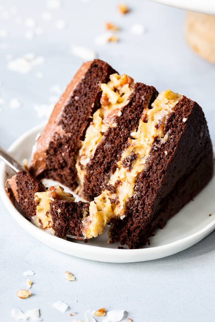 This rich Paleo German Chocolate Cake has a classic coconut pecan filling between tender grain free chocolate cake layers, and is topped with a dairy-free, refined sugar free chocolate frosting.  A showstopper for any gathering, this healthy German Chocolate Cake will become a family favorite!