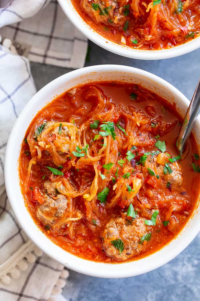 This healthy spaghetti and meatball soup uses spaghetti squash instead of pasta to make it lower in carbs, gluten-free, paleo and Whole30 compliant!  This savory, cozy soup is the perfect answer to your spaghetti and meatball cravings! 