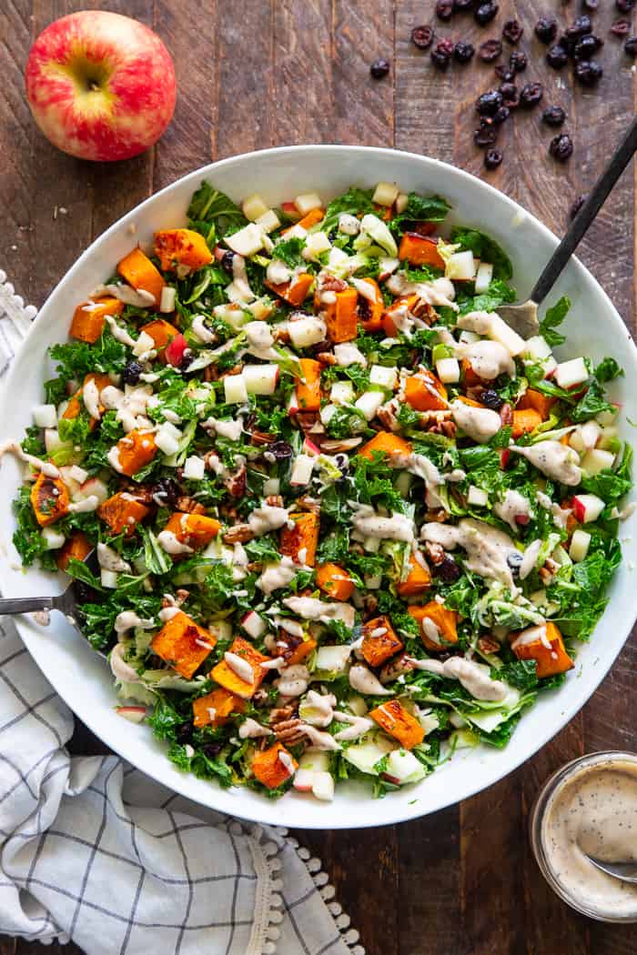 This roasted butternut squash salad is loaded up with goodies and good for you ingredients! Caramelized butternut squash with sweet crisp apples, dried cranberries, toasted pecans, kale and Brussels sprouts all tossed in a creamy Whole30 compliant poppy seed dressing.  Paleo, vegan, dairy-free, gluten-free, and Whole30. 