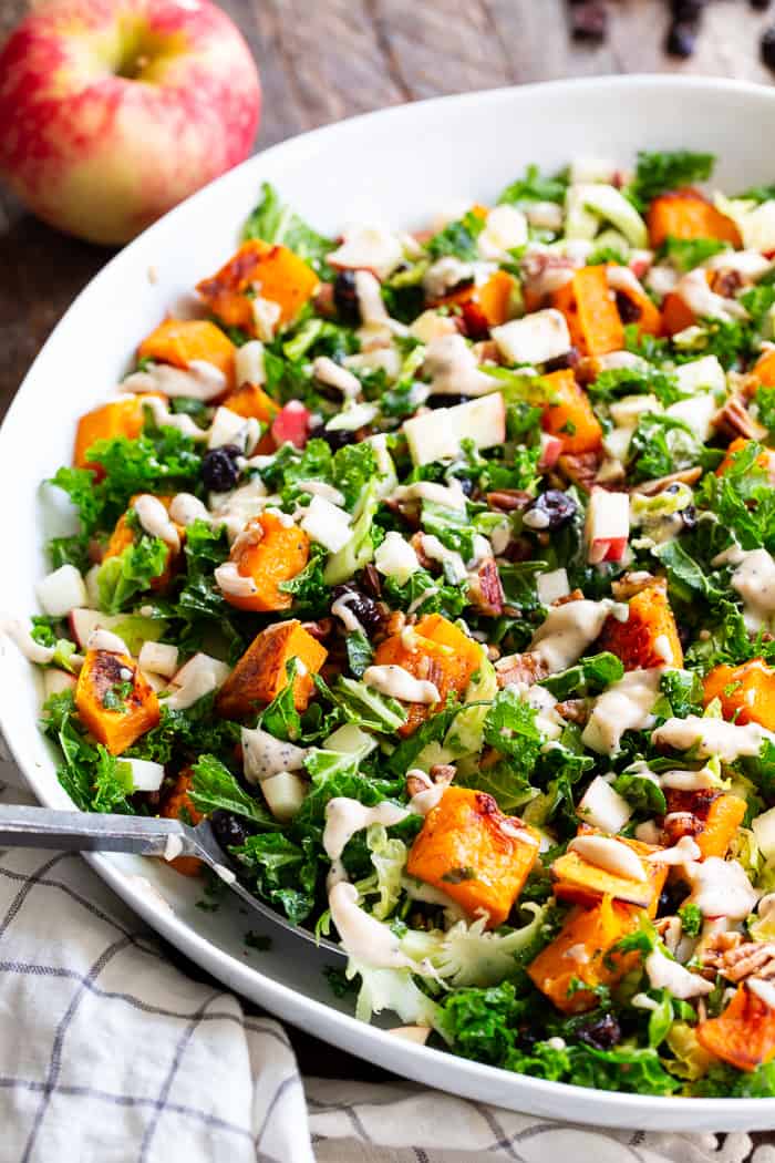 This roasted butternut squash salad is loaded up with goodies and good for you ingredients! Caramelized butternut squash with sweet crisp apples, dried cranberries, toasted pecans, kale and Brussels sprouts all tossed in a creamy Whole30 compliant poppy seed dressing.  Paleo, vegan, dairy-free, gluten-free, and Whole30. 