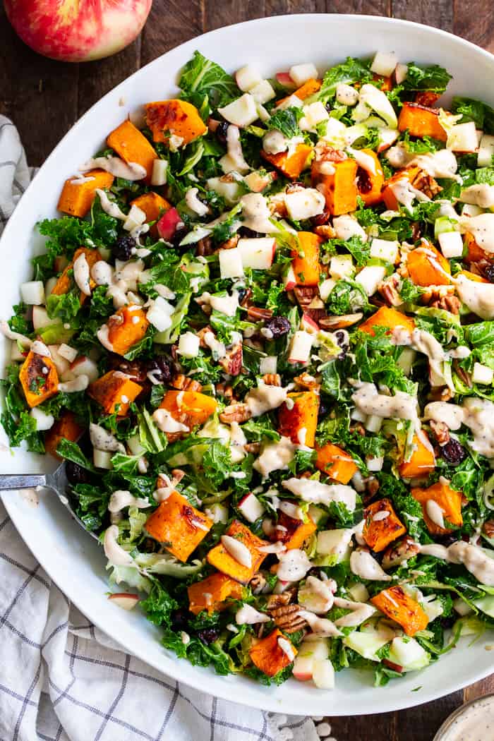This roasted butternut squash salad is loaded up with goodies and good for you ingredients! Caramelized butternut squash with sweet crisp apples, dried cranberries, toasted pecans, kale and Brussels sprouts all tossed in a creamy Whole30 compliant poppy seed dressing.  Paleo, vegan, dairy-free, gluten-free, and Whole30. 