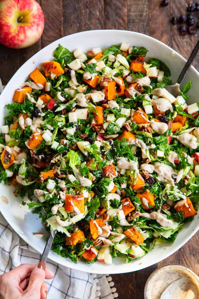 This roasted butternut squash salad is loaded up with goodies and good for you ingredients! Caramelized butternut squash with sweet crisp apples, dried cranberries, toasted pecans, kale and Brussels sprouts all tossed in a creamy Whole30 compliant poppy seed dressing.  Paleo, vegan, dairy-free, gluten-free, and Whole30. 