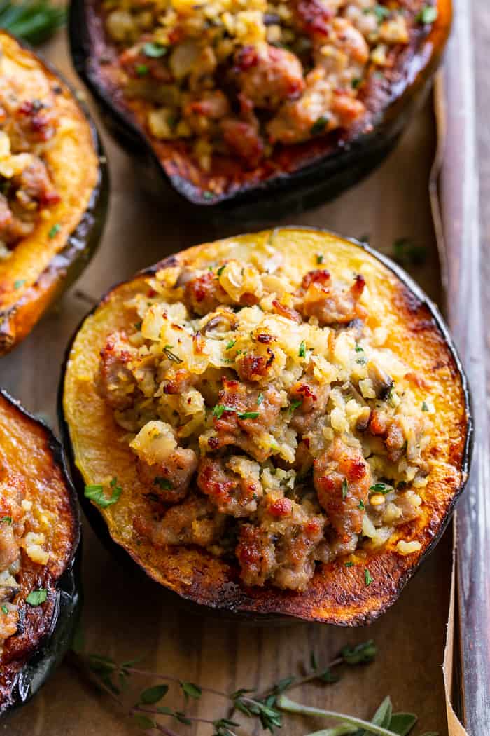 This savory stuffed acorn squash is so delicious it’s addicting!  A sausage and cauliflower rice stuffing is seasoned with lots of fresh herbs and served toasty in roasted acorn squash bowls.  Perfect as a holiday side dish or an anytime meal.  Paleo, Whole30, and low in carbs.