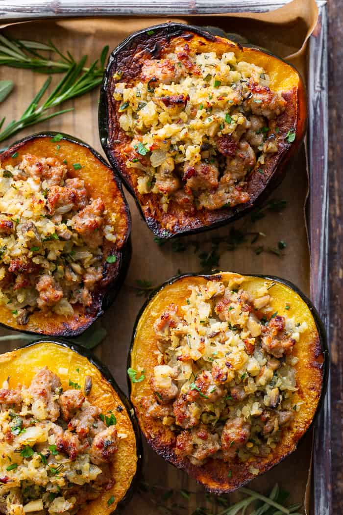 This savory stuffed acorn squash is so delicious it’s addicting!  A sausage and cauliflower rice stuffing is seasoned with lots of fresh herbs and served toasty in roasted acorn squash bowls.  Perfect as a holiday side dish or an anytime meal.  Paleo, Whole30, and low in carbs.