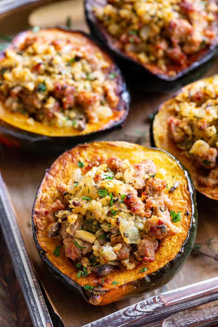 This savory stuffed acorn squash is so delicious it’s addicting!  A sausage and cauliflower rice stuffing is seasoned with lots of fresh herbs and served toasty in roasted acorn squash bowls.  Perfect as a holiday side dish or an anytime meal.  Paleo, Whole30, and low in carbs.