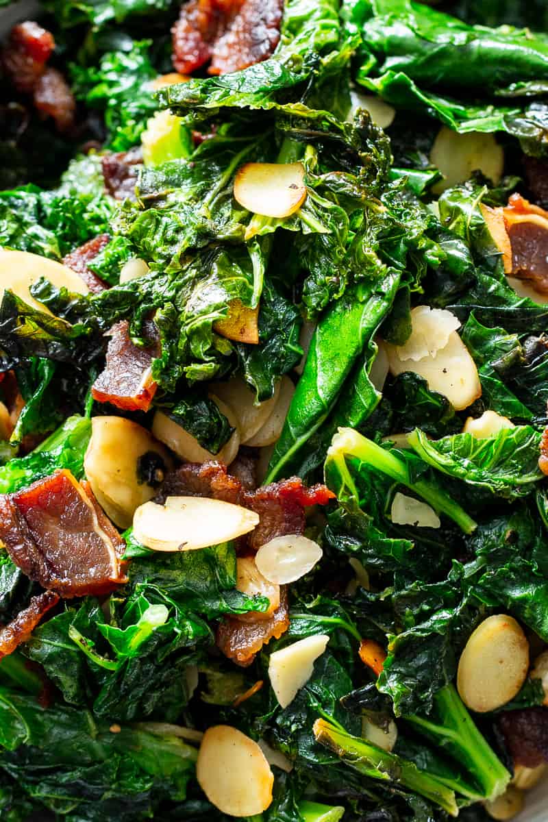 This delicious and simple sautéed kale with bacon and almonds is a savory healthy side dish that you’ll want on repeat!  It’s paleo and Whole30 friendly, keto, and Low FODMAP.  Serve it with any main course to add lots of flavor and nutrients to your meal. #keto #cleaneating #paleo #whole30 #lowfodmap