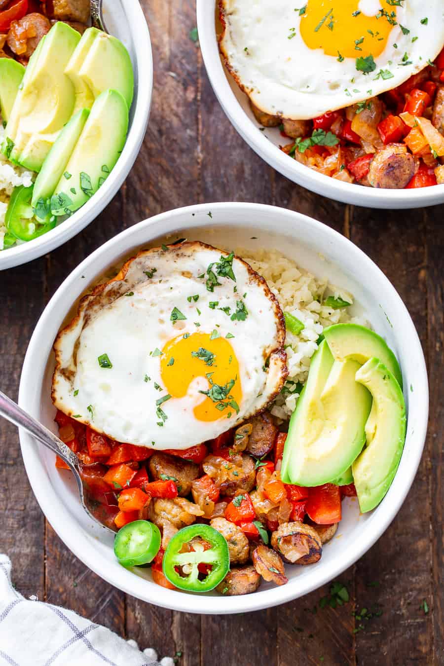 These Paleo breakfast burrito bowls are loaded with goodies!  Savory No Antibiotics Ever All Natural Golden Brown Chicken Sausage, peppers, onions, and seasoned cauliflower rice topped with sliced avocado and eggs. These delicious breakfast bowls are low carb, Whole30 compliant and super easy to throw together!