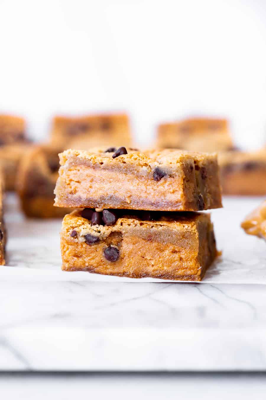 These super fudgy chocolate chip blondies are stuffed with a thick fudgy layer of nut butter for the dreamiest “peanut” butter stuffed blondies you’ll ever make!  They’re gluten free, dairy free, vegan, egg free and insanely delicious! #vegan #paleo #glutenfree