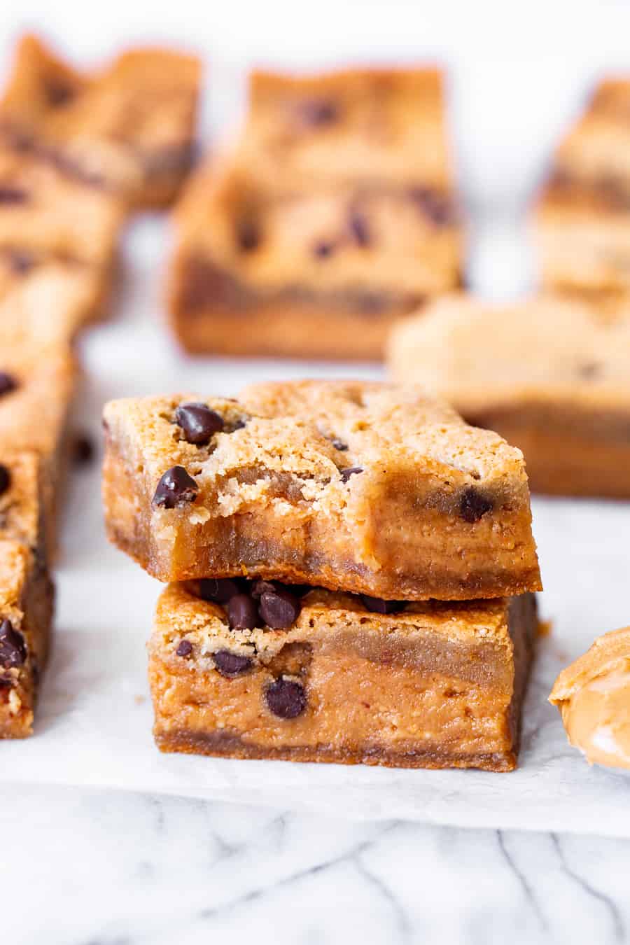 These super fudgy chocolate chip blondies are stuffed with a thick fudgy layer of nut butter for the dreamiest “peanut” butter stuffed blondies you’ll ever make!  They’re gluten free, dairy free, vegan, egg free and insanely delicious! #vegan #paleo #glutenfree