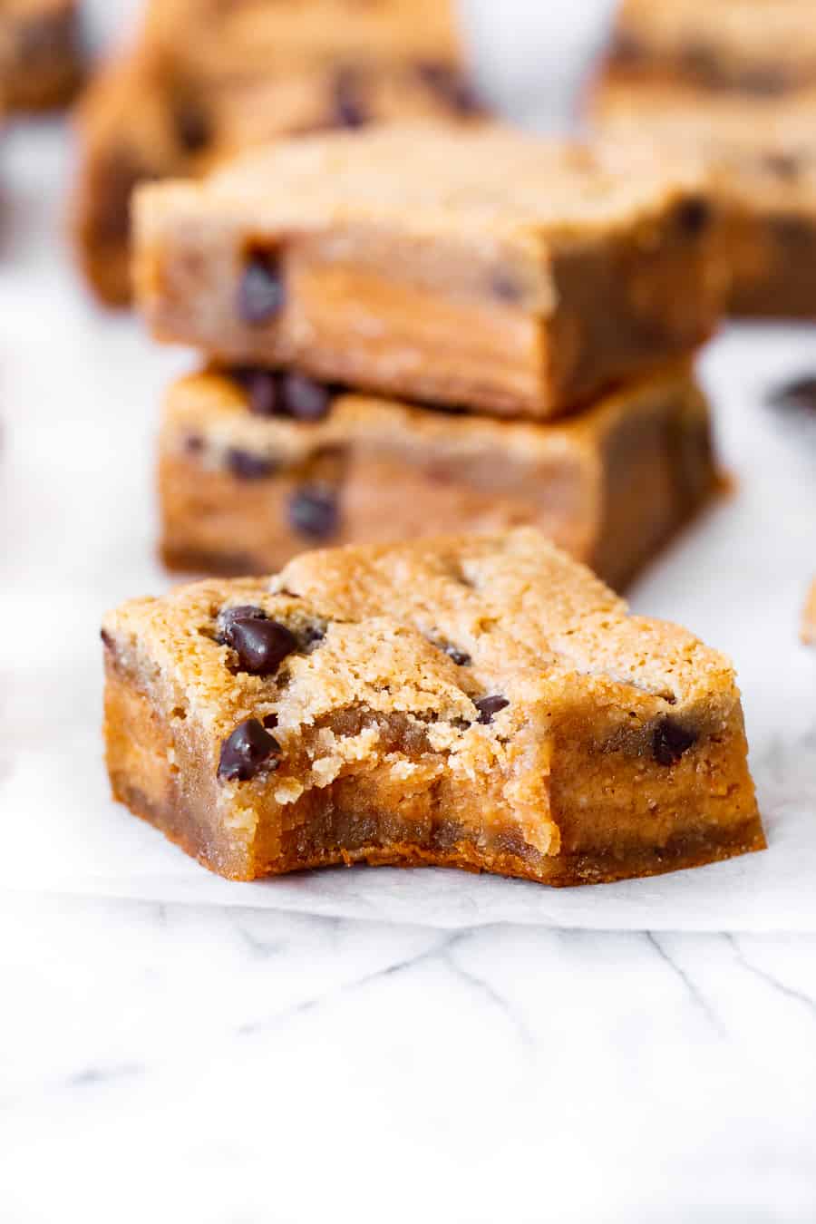 These super fudgy chocolate chip blondies are stuffed with a thick fudgy layer of nut butter for the dreamiest “peanut” butter stuffed blondies you’ll ever make!  They’re gluten free, dairy free, vegan, egg free and insanely delicious! #vegan #paleo #glutenfree