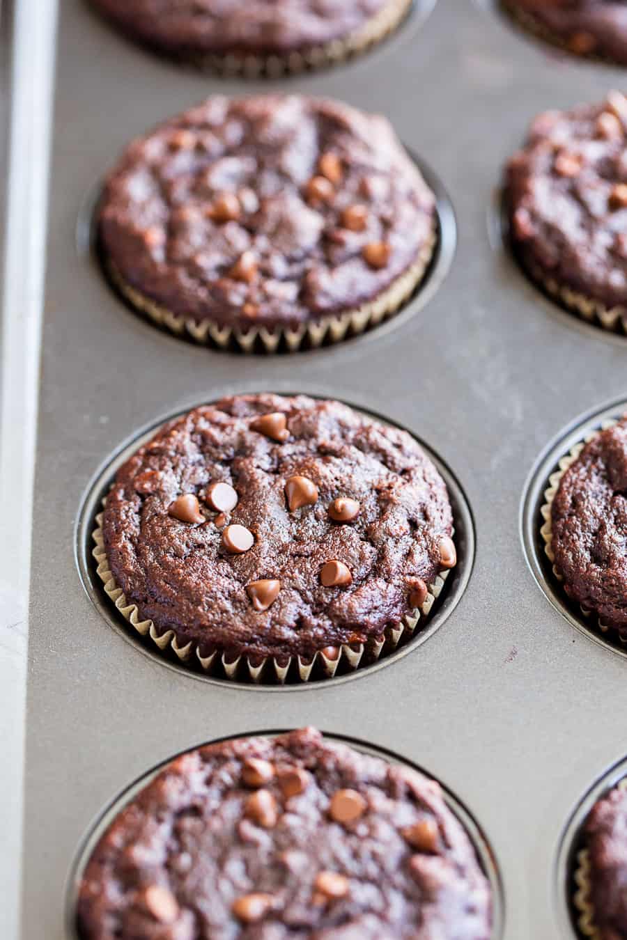 These moist and tender double chocolate banana muffins are quick and easy to make and taste just as decadent as rich chocolate cupcakes!  Made with coconut flour and raw cacao powder so they’re paleo plus nut free, gluten free, and dairy free.  Kid approved and great for snacks and dessert! #paleorecipes #bananamuffins #paleo #paleobaking #glutenfree #coconutflour