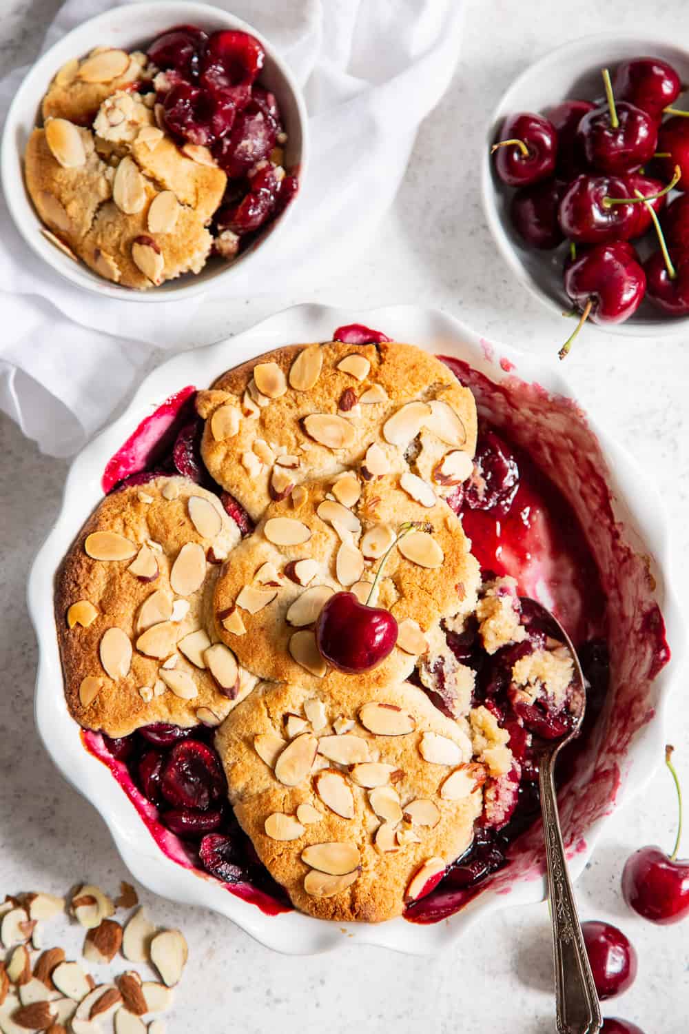 This paleo and vegan cherry almond cobbler is sure to become a family favorite.  A sweet fresh cherry filling is baked with a biscuit cobbler topping and toasty almonds that’s gluten free, dairy free, and egg free.  It’s perfect served with a big scoop of coconut vanilla ice cream or on its own!  Easy to make and the perfect healthy dessert for Summer. #ad @chelanfresh #cherries #paleo #vegan #glutenfree 
