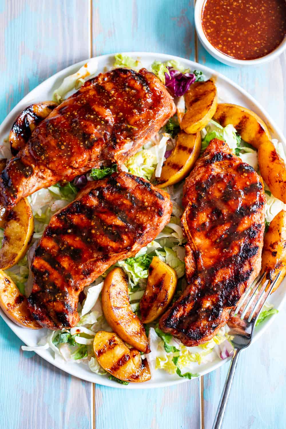 These easy paleo grilled pork chops have a simple and delicious used as both a marinade and dipping sauce for extra flavor.  The peaches add sweet summer flair to the chops which you can serve with any of your favorite sides!  Gluten free, dairy free, soy free, refined sugar free and a Whole30 option.  #paleo #cleaneating #Whole30 #porkchops 