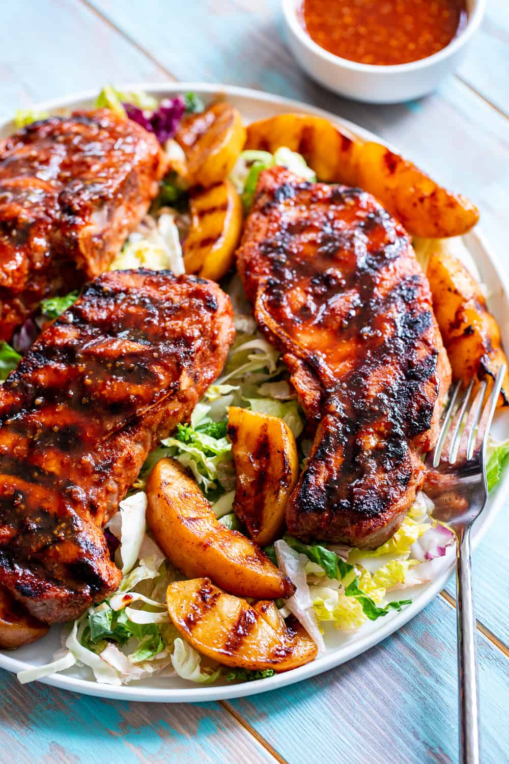 These easy paleo grilled pork chops have a simple and delicious used as both a marinade and dipping sauce for extra flavor.  The peaches add sweet summer flair to the chops which you can serve with any of your favorite sides!  Gluten free, dairy free, soy free, refined sugar free and a Whole30 option.  #paleo #cleaneating #Whole30 #porkchops 