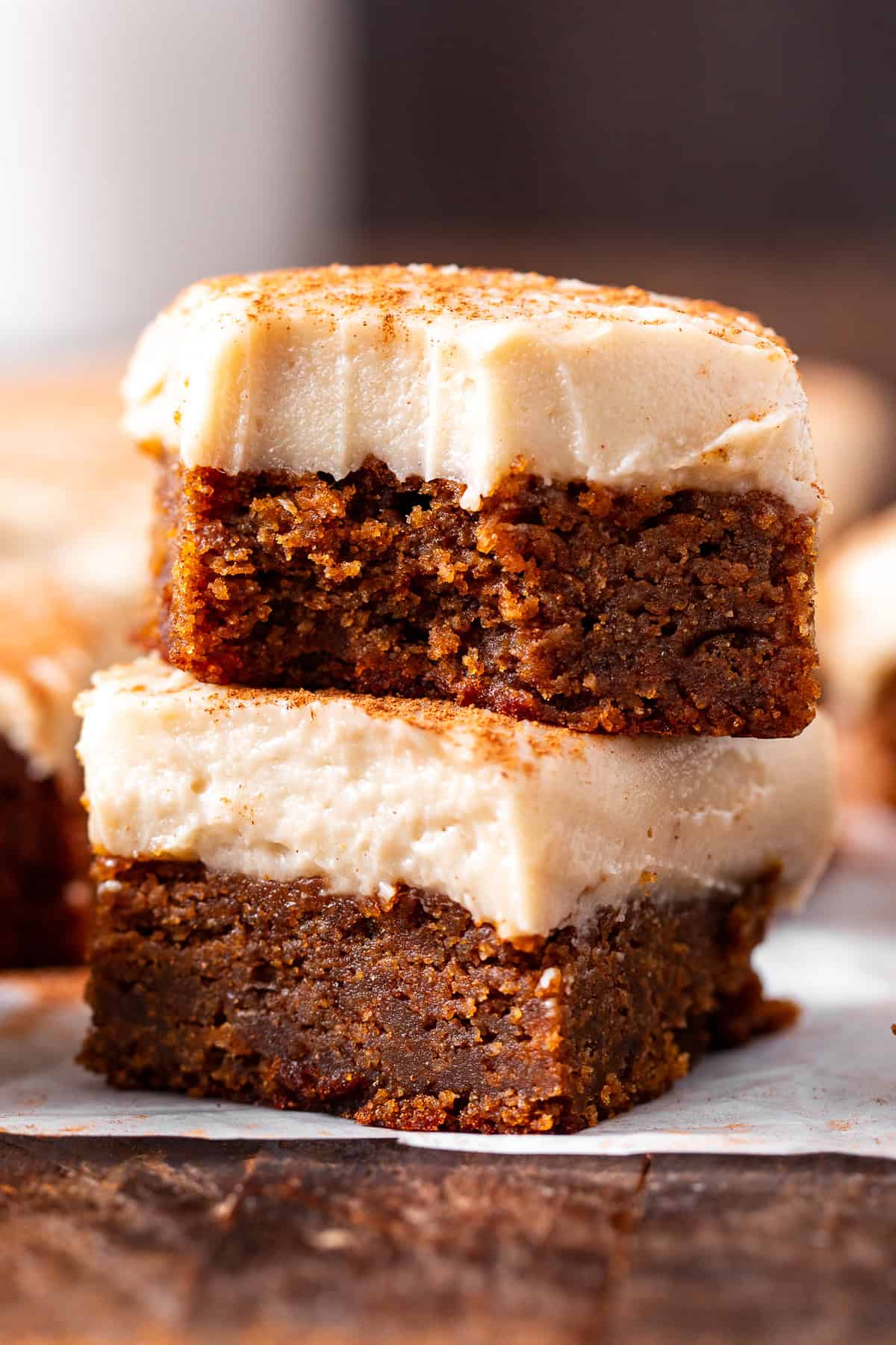 Close up stack of two paleo pumpkin bars with dairy-free cream cheese frosting