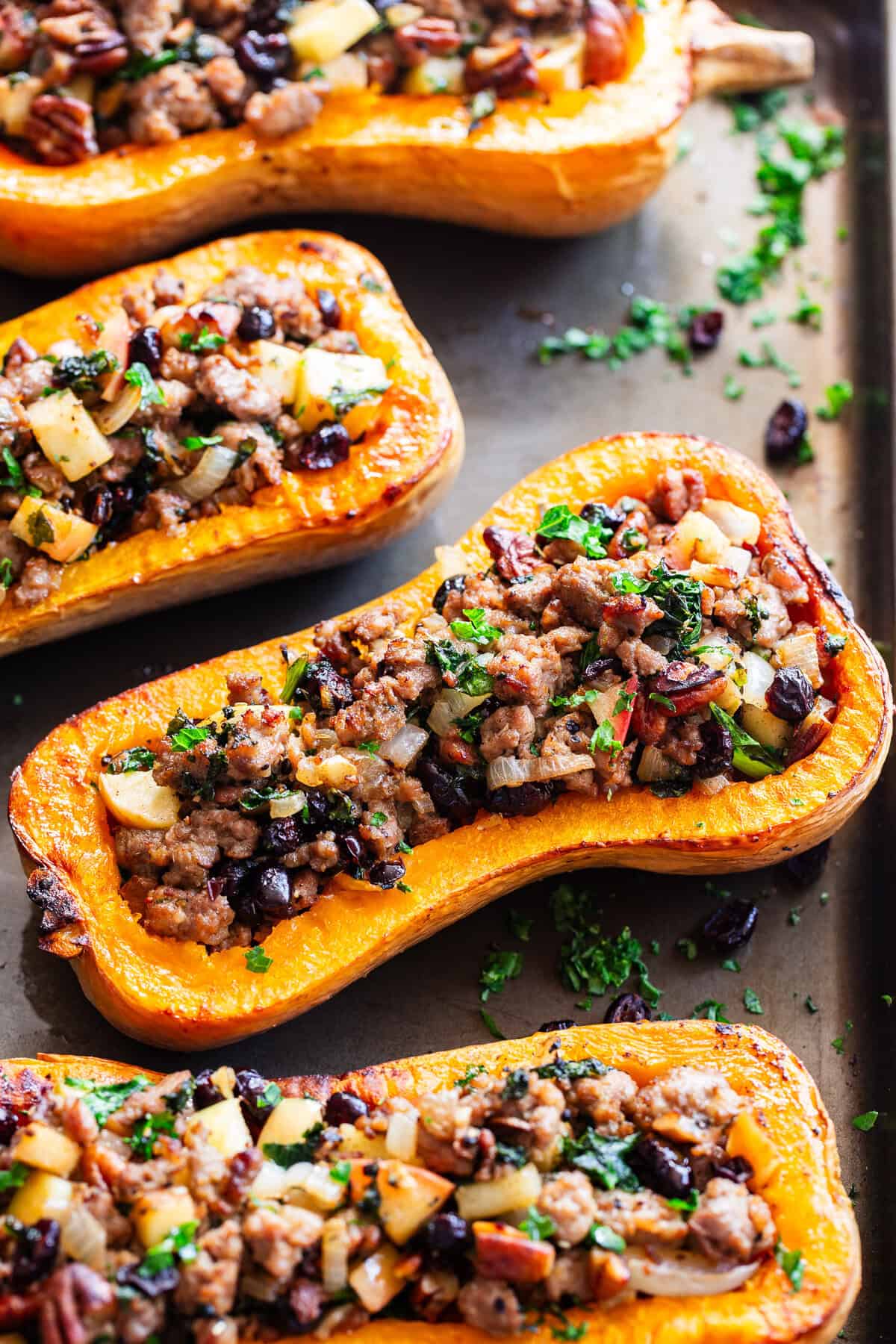 Roasted stuffed butternut squash is filled with a savory-sweet mixture of Italian sausage, apples, cranberries, kale, pecans and fresh herbs.
