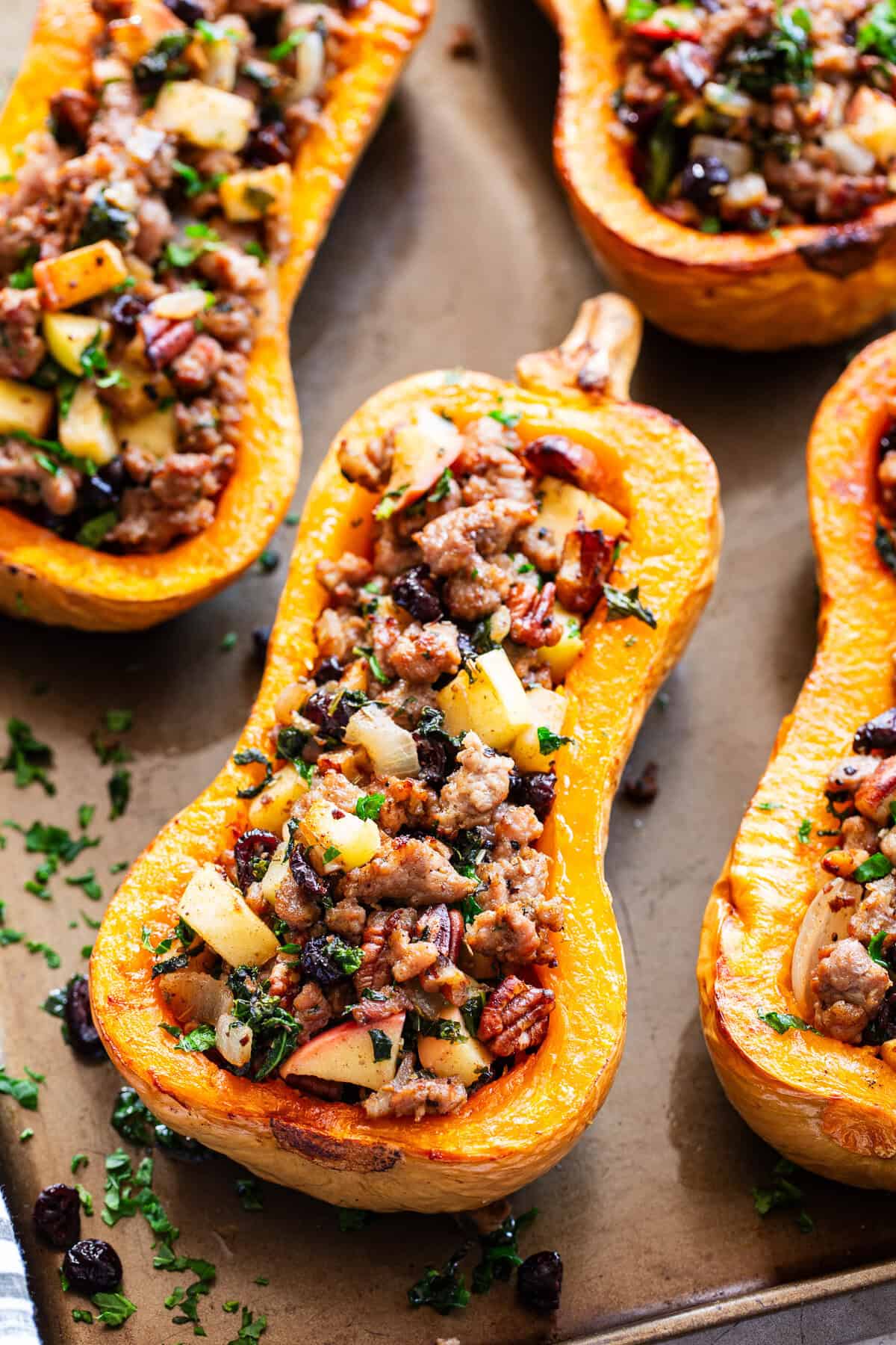 Roasted stuffed butternut squash is filled with a savory-sweet mixture of Italian sausage, apples, cranberries, kale, pecans and fresh herbs.