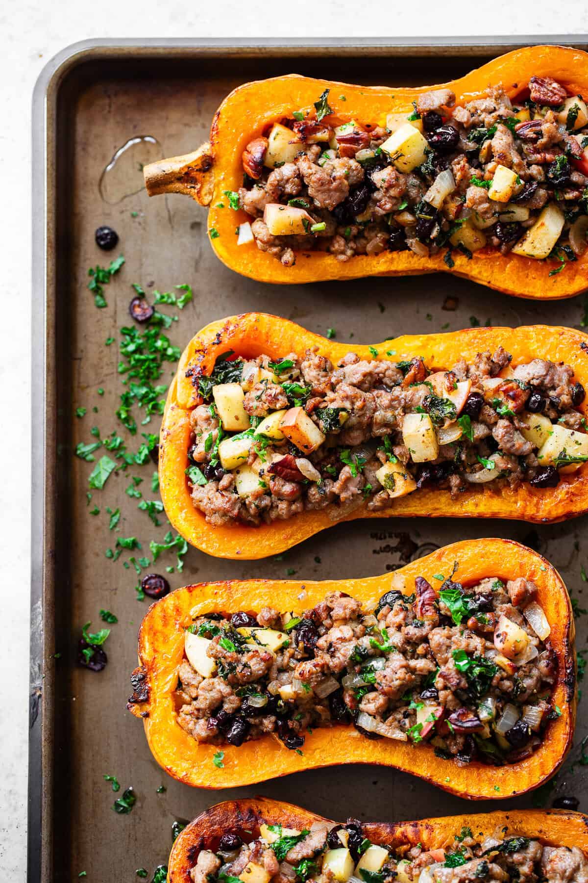 Roasted stuffed butternut squash is filled with a savory-sweet mixture of Italian sausage, apples, cranberries, kale, pecans and fresh herbs.