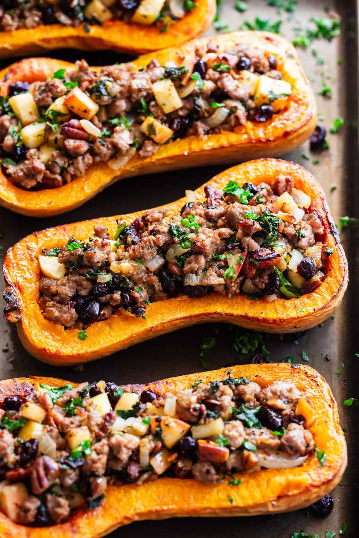 Roasted stuffed butternut squash is filled with a savory-sweet mixture of Italian sausage, apples, cranberries, kale, pecans and fresh herbs.