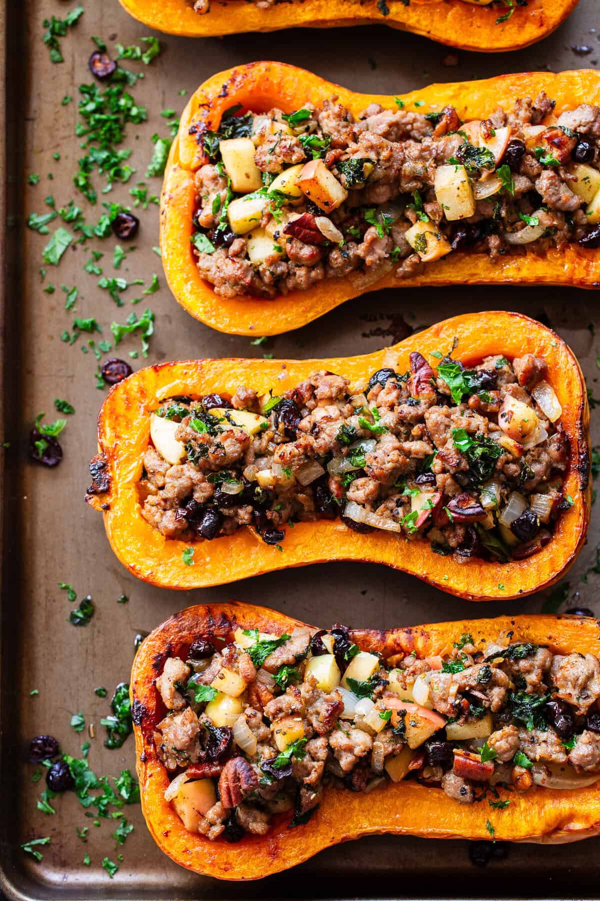 Roasted stuffed butternut squash is filled with a savory-sweet mixture of Italian sausage, apples, cranberries, kale, pecans and fresh herbs.