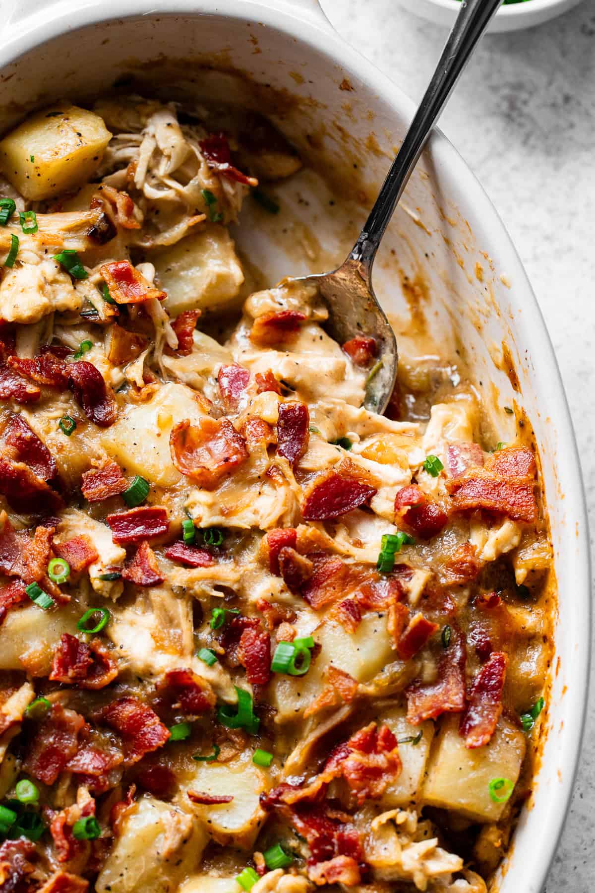 Spoon serving creamy chicken potato casserole with bacon and potatoes