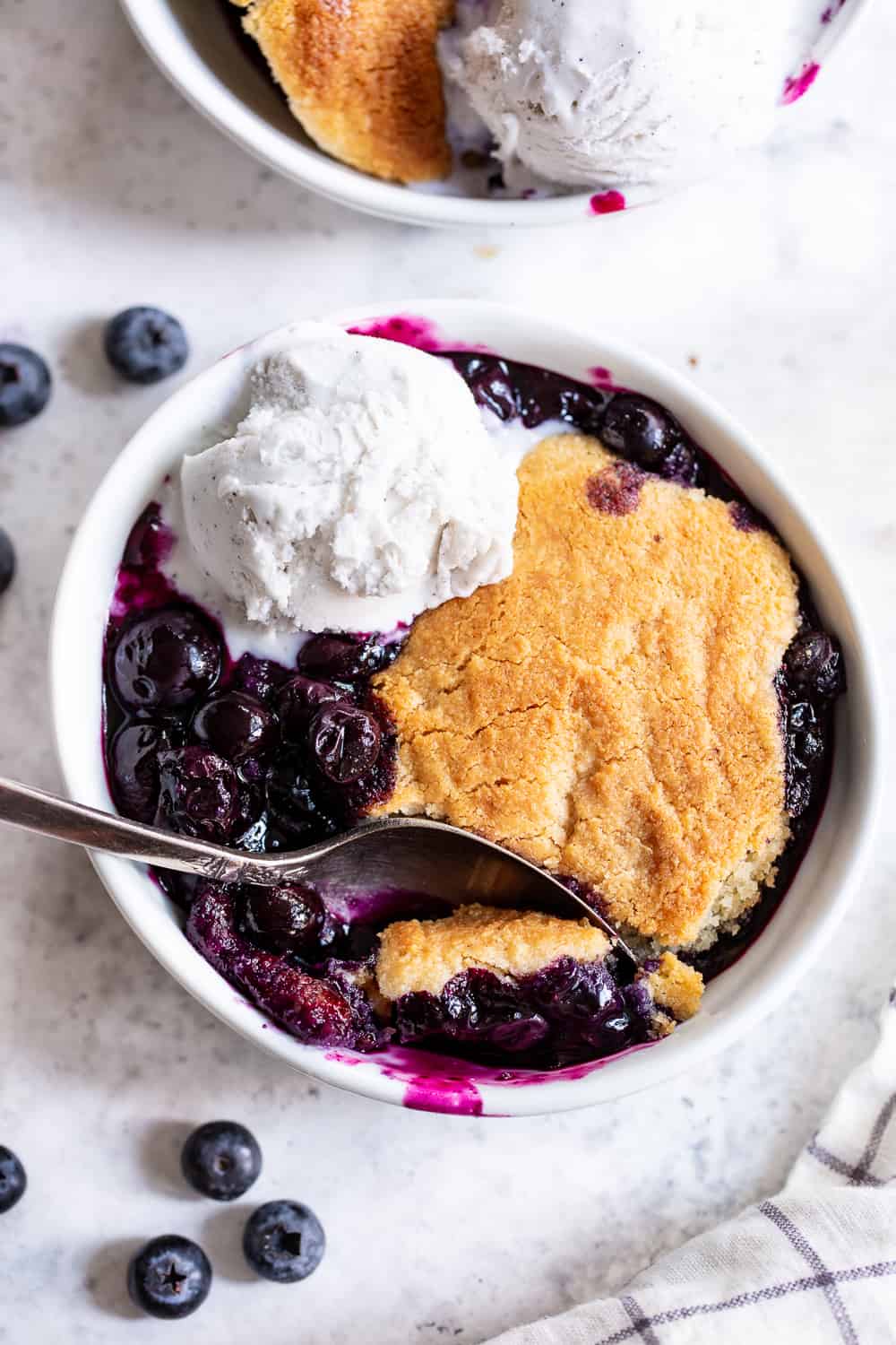 This paleo and vegan blueberry cobbler has quickly become a family favorite! A sweet gooey blueberry layer is baked with a biscuit cobbler topping that’s gluten free, dairy free, and egg free. It’s perfect served with a big scoop of coconut vanilla ice cream or on its own! Easy to make and the perfect healthy dessert for Spring and Summer. #paleo #vegan #cobbler #glutenfree #paleobaking #cleaneating #glutenfreedessert