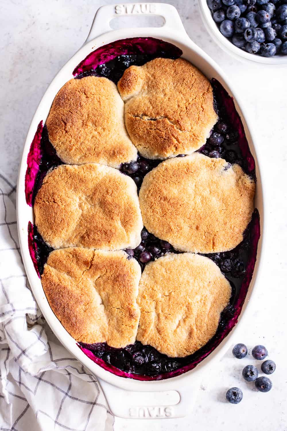 This paleo and vegan blueberry cobbler has quickly become a family favorite! A sweet gooey blueberry layer is baked with a biscuit cobbler topping that’s gluten free, dairy free, and egg free. It’s perfect served with a big scoop of coconut vanilla ice cream or on its own! Easy to make and the perfect healthy dessert for Spring and Summer. #paleo #vegan #cobbler #glutenfree #paleobaking #cleaneating #glutenfreedessert