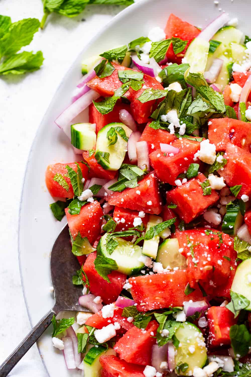 This simple and refreshing watermelon salad has all the flavors you’re craving!  Juicy watermelon with cucumber, red onion, basil, mint and dairy free feta cheese tossed in a super simple vinaigrette.  It’s healthy, paleo, vegan, and perfect for hot summer BBQs and picnics! #paleo #vegan #cleaneating