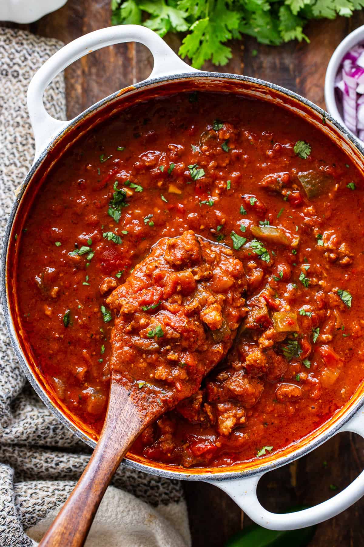 Thick homemade pumpkin chili with ground beef shown on a wooden spoon