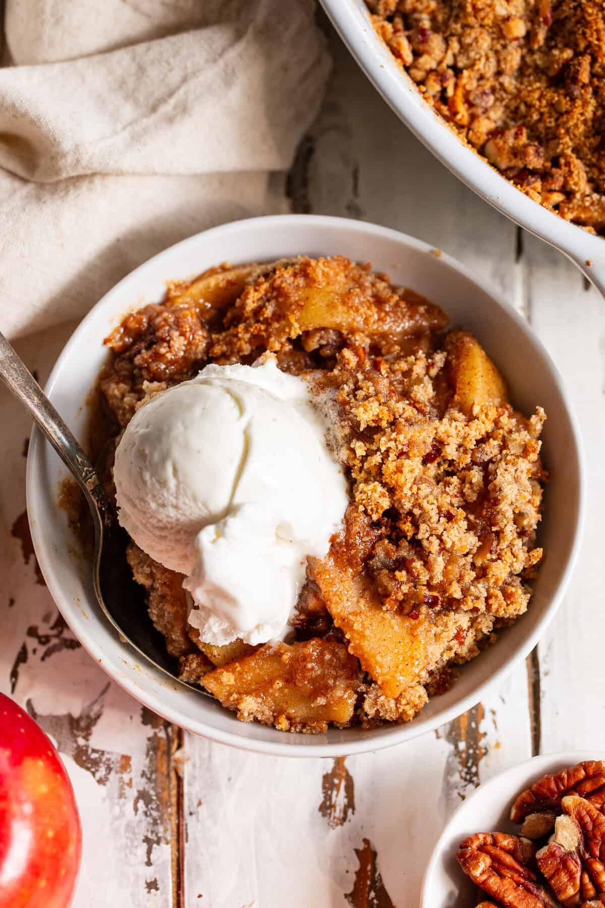 Paleo apple crisp topped with vanilla ice cream and crunchy pecan crumble